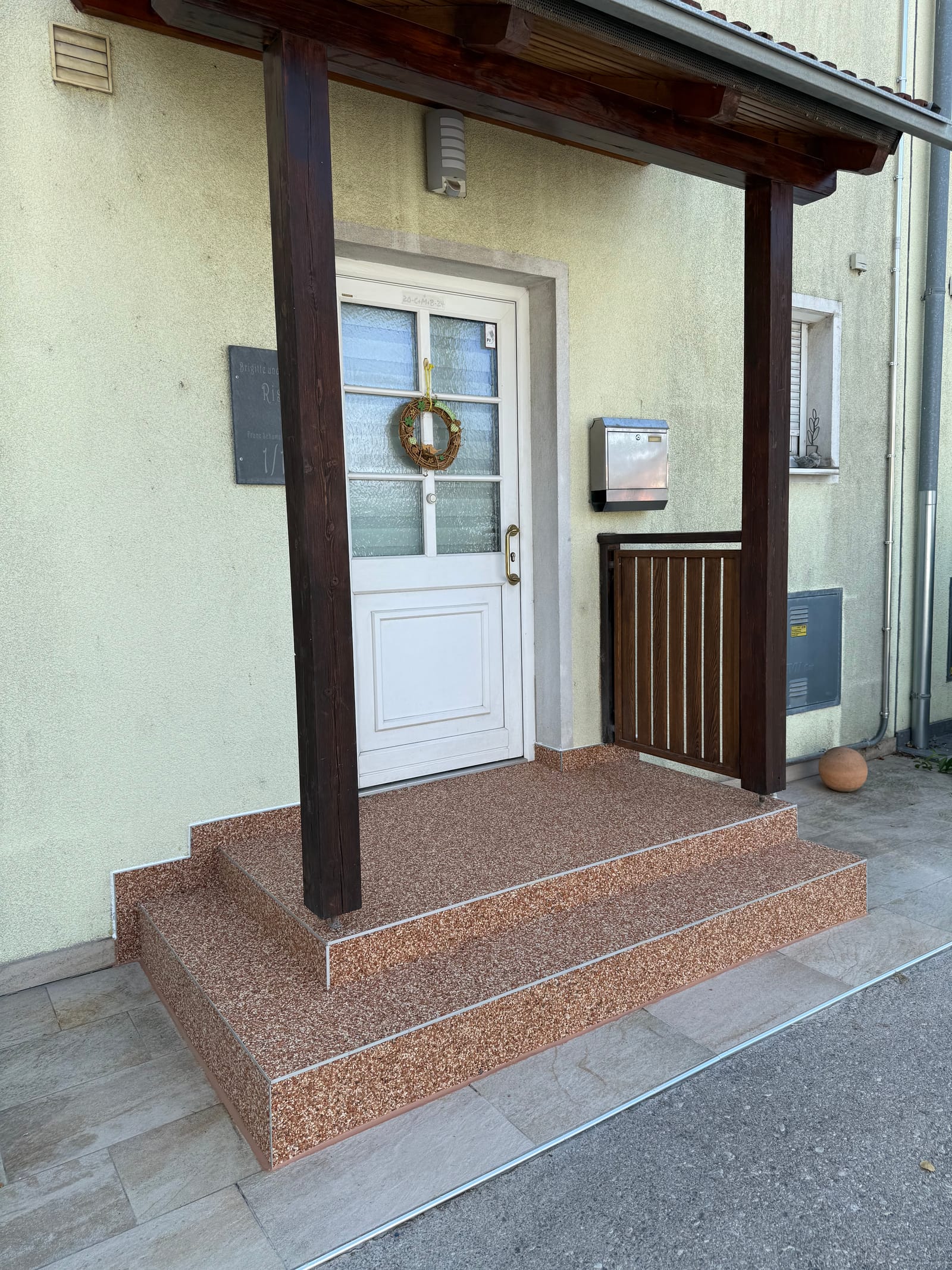 Hauseingang mit Natursteinteppich-Stufen in Terracotta unter Holz-Vordach, rutschfeste Steinbeschichtung